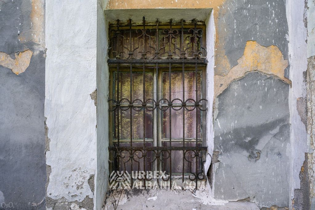 Fenêtre du rez-de-chaussée du sanatorium derrière une ancienne grille en fer ouvragée