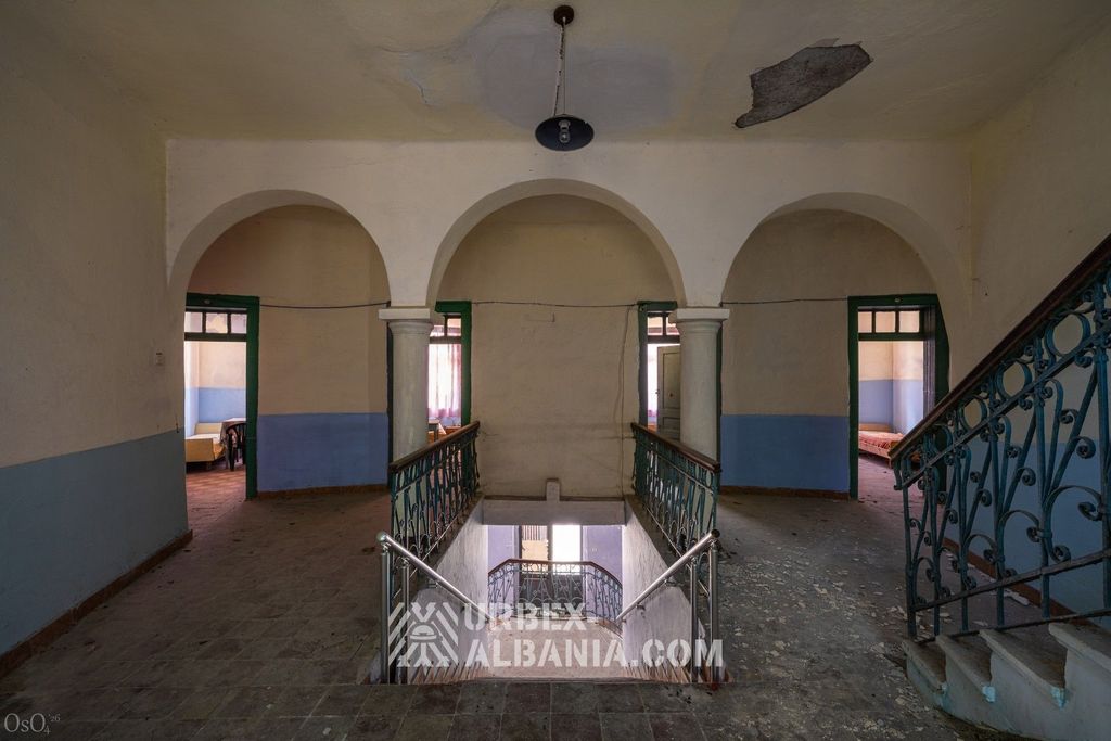 Hall principal du sanatorium abandonné avec de hautes fenêtres et le comptoir de réception déserté
