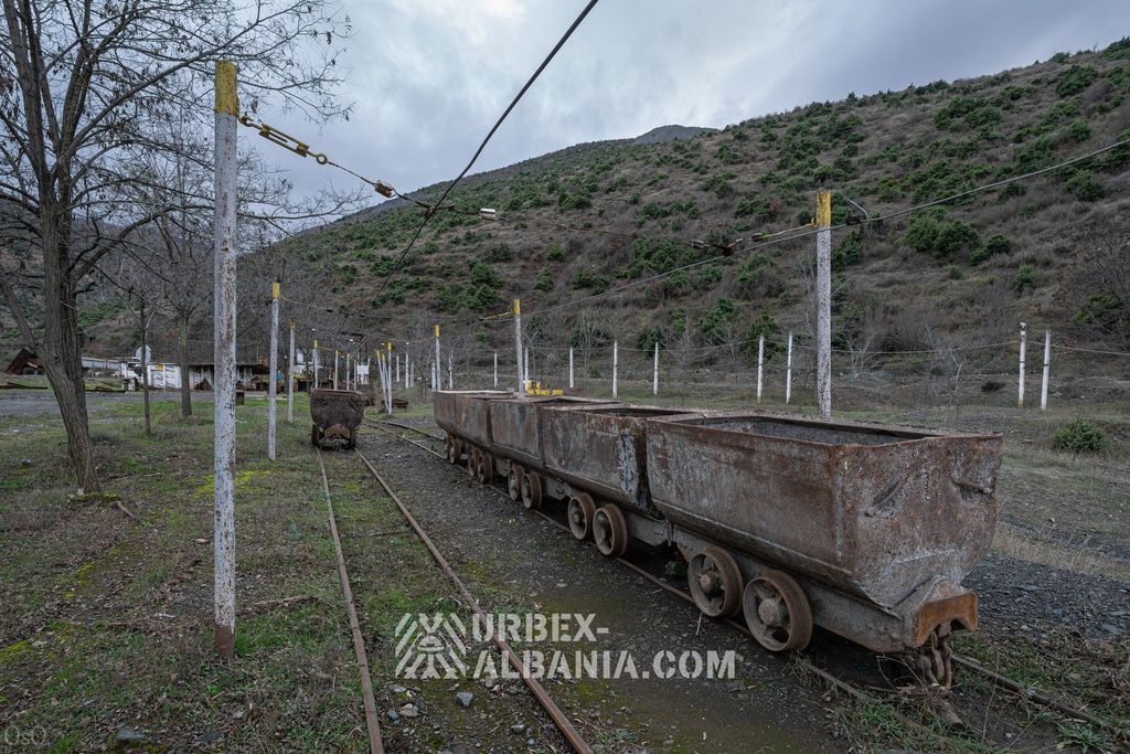 Состав ржавых вагонеток на поверхностном пути под троллейным проводом