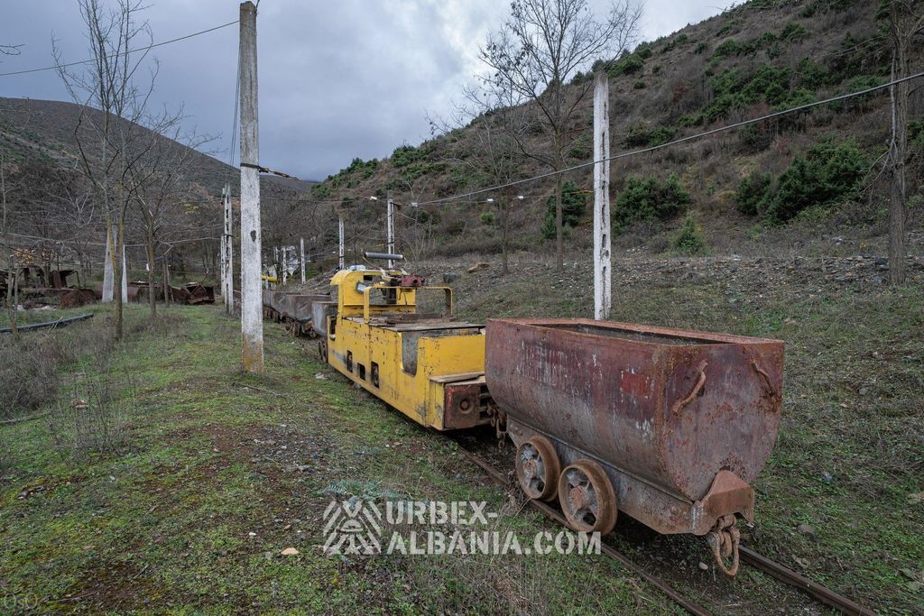 Жёлтый троллейный электровоз, сцепленный с вагонетками на поверхностном пути