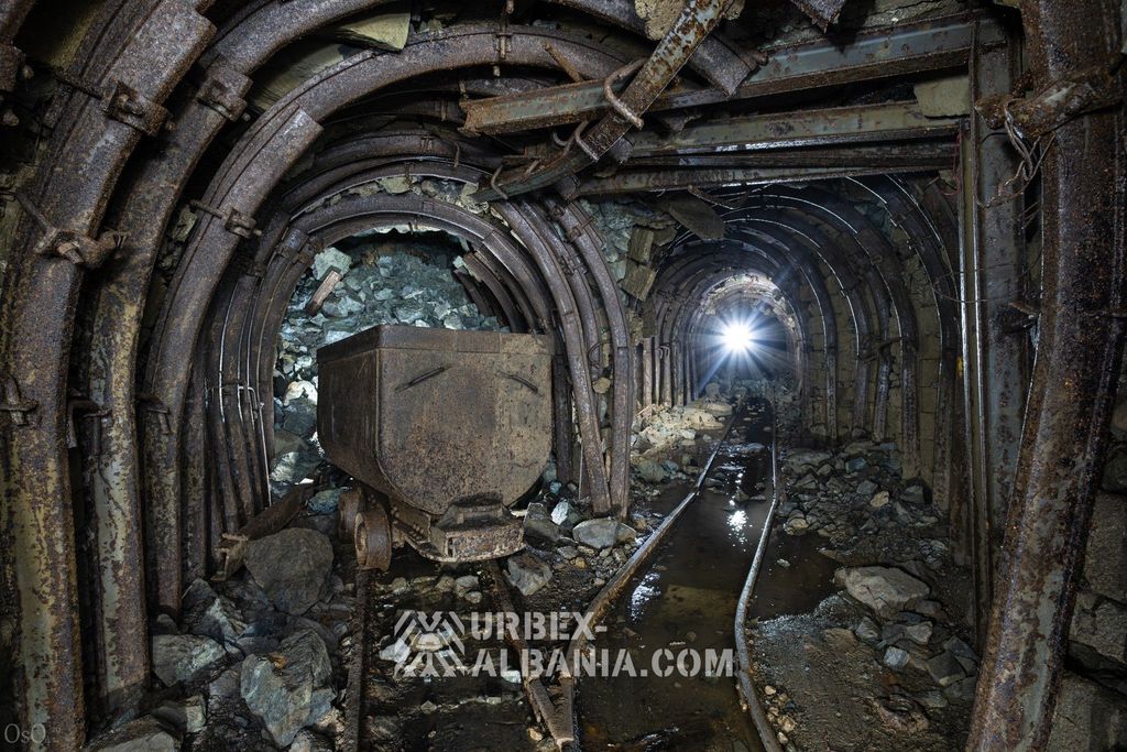 Вагонетка рядом с обрушением, просыпавшимся сквозь арочную крепь выработки
