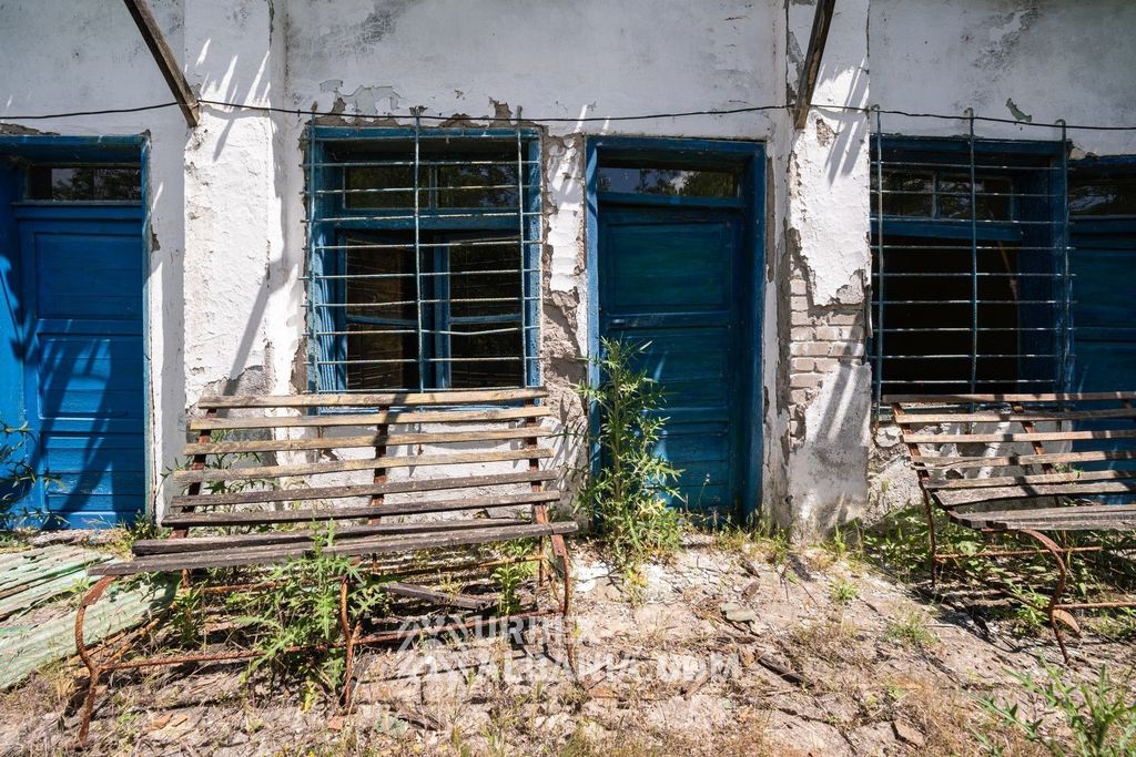 Bancs posés dans l'herbe devant chacune des portes du baraquement du sanatorium