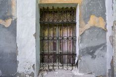 Fenêtre du rez-de-chaussée du sanatorium derrière une ancienne grille en fer ouvragée