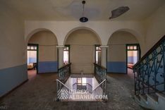Hall principal du sanatorium abandonné avec de hautes fenêtres et le comptoir de réception déserté