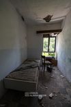 Chambre simple sinistre du sanatorium avec un sommier nu près de la fenêtre