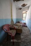 Chambre simple étroite avec un lit et des murs nus, plus proche d'une cellule que d'une chambre d'hôtel