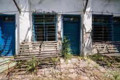 Bancs posés dans l'herbe devant chacune des portes du baraquement du sanatorium
